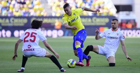 Sergi Guardiola pasa entre dos jugadores del Sevilla en el Nuevo Mirandilla